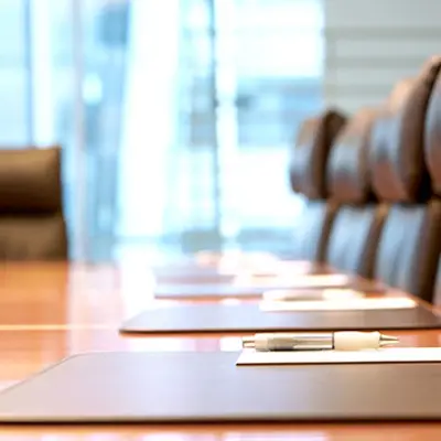 empty chairs in a boardroom at a boardroom table with a window in the background