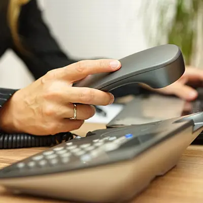 close up of a hand picking up a landline phone in an office