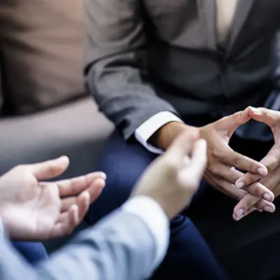 close up of hands of two people sitting across from each other, one with hands open and palms up, one with hands clasped