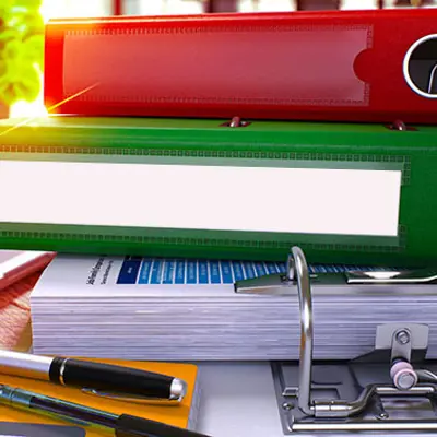 a stack of binders, one red, one green and one white, on a table